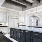 A luxury kitchen with custom cabinetry and layered lighting, featuring pendant lights over a large island, recessed ceiling lights, and elegant finishes that highlight the space’s architectural details.
